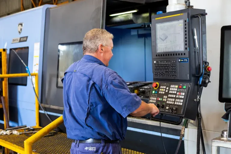 Machine operator programming a CNC milling machine to produce a part for a client