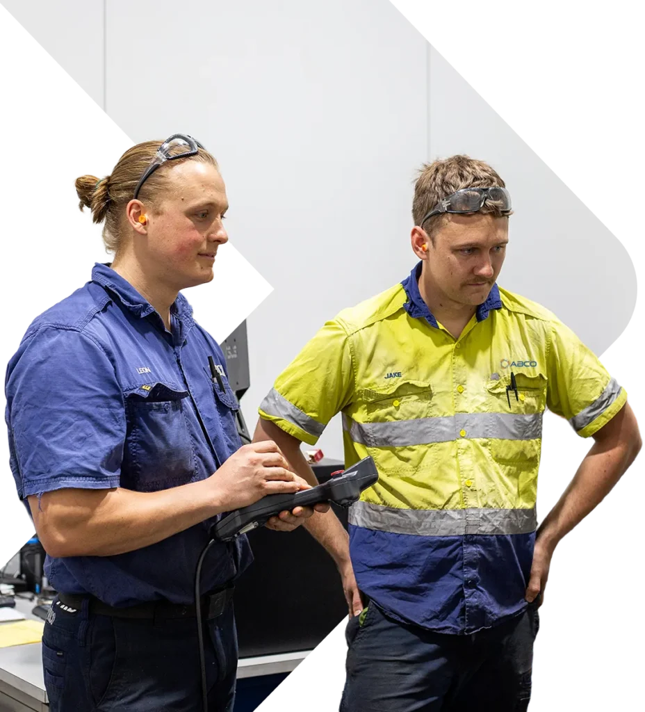 Decorative image of two ABCO Precision Machining employees working on a CMM machine