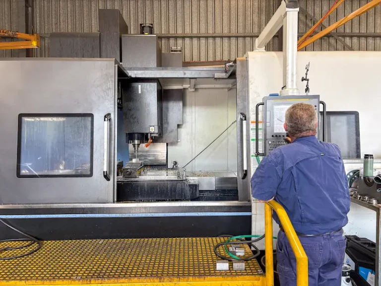 Machine operator programming a CNC milling machine to produce a part for a client in Australia
